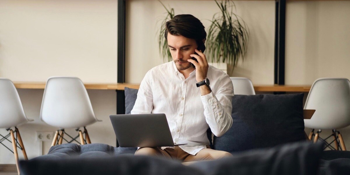 Developer working on laptop and talking on the mobile phone