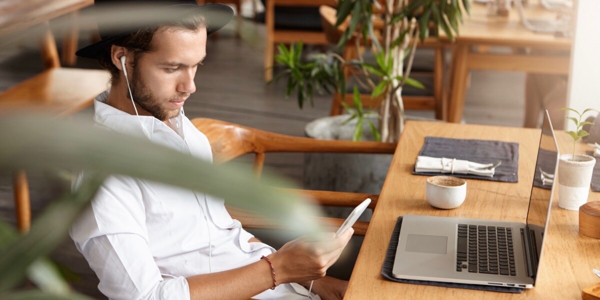 Freelancer sitting at cafe table with laptop